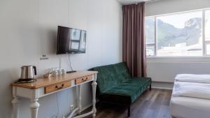 Habitación de hotel con silla verde y TV en Guesthouse Hamar en Islas Vestman