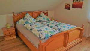 ein Holzbett mit blauer und weißer Bettwäsche und Kissen in der Unterkunft Ferienwohnung Sommerwind in Rhauderfehn