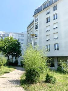 a tall white building with bushes in front of it at Studio 30m2 - Au pied de la Gare - PARKING in Cergy