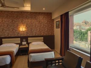a hotel room with two beds and a window at Hotel Deepam in Tiruchchirāppalli