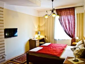 ein Hotelzimmer mit einem roten Bett und einem Schreibtisch in der Unterkunft Hotel Janków in Żary