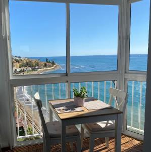 una mesa y sillas en una habitación con vistas al océano en Estudio Edificio Almirante, en Mijas Costa