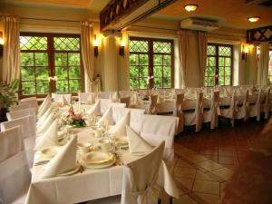 ein Raum mit weißen Tischen und Stühlen in einem Raum mit Fenstern in der Unterkunft Hotel Janków in Żary