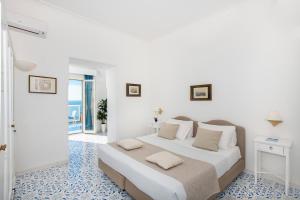 a white bedroom with a large bed with two pillows at Grand Hotel Tritone in Praiano