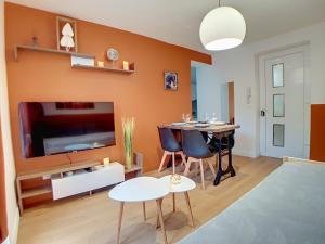 a living room with an orange wall with a dining table at Stop Chez M Select Saga # Qualité # Confort # Simplicité in Saint-Fons