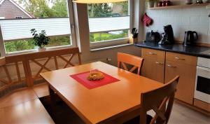 a kitchen with a wooden table with a bowl of fruit on it at Ferienwohnung Sommerwind in Rhauderfehn