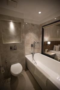 a bathroom with a tub and a toilet and a bed at The Flora Grand, Vasco, Goa in Vasco Da Gama