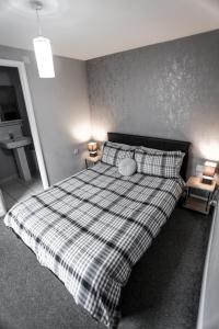 a bedroom with a large bed with a plaid blanket at No 3 New Inn Apartments NEWLY RENOVATED in Newark-on-Trent