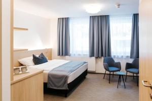 a hotel room with a bed and two chairs at Sankt Magdalena in Linz