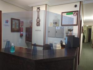 um quarto com uma secretária com cadeiras e um relógio na parede em Hostal Palas em La Coruña