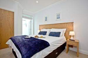 a white bedroom with a large bed and a table at 3 Goodrington Lodge, Paignton in Paignton