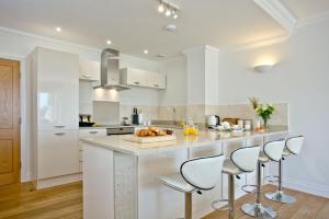 a kitchen with white cabinets and a counter with stools at 3 Goodrington Lodge, Paignton in Paignton