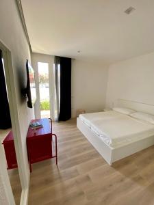 1 dormitorio con cama blanca y mesa roja en Residenza Acqva di Mare, en Cagliari