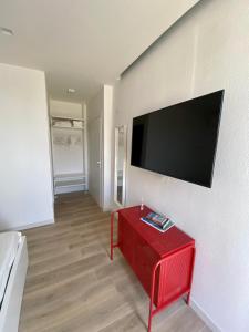 sala de estar con mesa roja y TV de pantalla plana en Residenza Acqva di Mare, en Cagliari