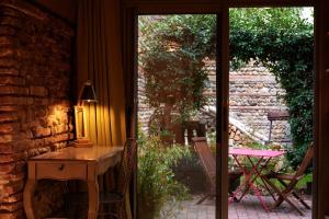 Cette chambre dispose d'une table et d'une porte donnant sur une terrasse. dans l'établissement Maison Anjali, à Toulouse