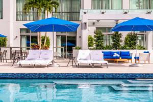a pool with chairs and umbrellas next to a building at Hyatt Centric Las Olas Fort Lauderdale in Fort Lauderdale