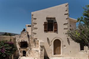 un edificio antiguo con ventanas y un árbol en Παραδοσιακή κατοικία Μαργαρίτες, en Margarítai