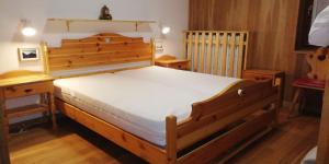una camera da letto con un grande letto in legno con lenzuola bianche di CasaMau Trilo a Campitello di Fassa