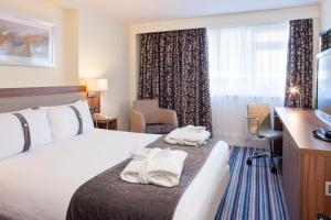 a hotel room with a bed and a desk and a window at Holiday Inn Rugby-Northampton M1 Jct18, an IHG Hotel in Crick