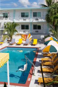 a beach area with a pool, chairs, and lawn chairs at Selina Gold Dust in Miami