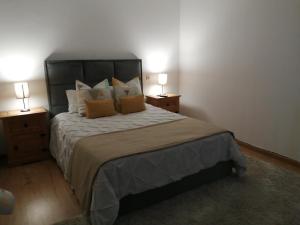een slaapkamer met een groot bed met 2 nachtkastjes bij Casa do Trovador in Serra