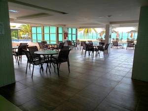 a dining room with tables and chairs and the ocean at Life Tabatinga Beach-Flat com Wi-Fi in Conde