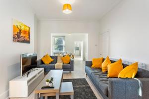 a living room with two blue couches and yellow pillows at Jasmine Villa A - Ideal for QMC & Uni - Free parking in Nottingham