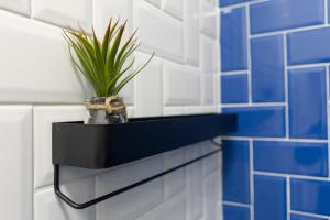 een plant op een plank in een blauw betegelde badkamer bij Adele I levestate in Wenen
