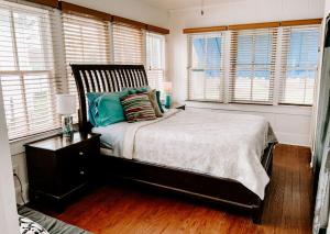 a bedroom with a bed with pillows and windows at Blue Moon Guest House in Lafayette
