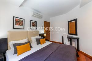 1 dormitorio con 1 cama grande con almohadas de color naranja y gris en Baia da Luz Resort, en Luz