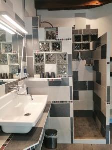 a bathroom with a sink and a tile wall at Le clos des augers, chambres d'hôtes et roulotte in Azay-sur-Cher
