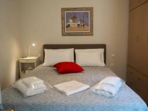 a bed with two towels and a red pillow on it at MOLLY's HOUSE in Ermoupoli