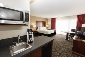 a hotel room with a bed and a kitchen with a sink at La Quinta by Wyndham Clearwater Central in Clearwater