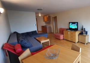 uma sala de estar com um sofá azul e uma televisão em Apartman 117 Vucko Jahorina em Jahorina