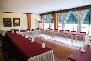 einen Konferenzraum mit roten und weißen Tischen und Stühlen in der Unterkunft Hotel & Suites Villa del Sol in Morelia