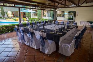 a long table with chairs in a room with a pool at Hotel & Suites Villa del Sol in Morelia