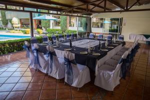 モレリアにあるHotel & Suites Villa del Solのプール付きの客室で、長テーブルと椅子が備わります。