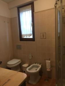 een badkamer met een toilet, een wastafel en een raam bij La casina nel Borgo in Cetona