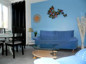 a living room with a blue couch and a table at La maison bleue in Fécamp