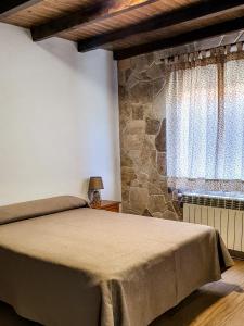 1 dormitorio con cama y pared de piedra en Complejo Turístico Las Cañadas Casas de Campo- Actividades Gratuitas Todos los Fines de Semana, en Baños de Montemayor