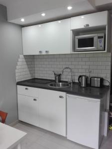 a kitchen with white cabinets and a sink and a microwave at Alfastudio in Breuil-Cervinia