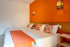 Pousada Dom Capudi في بومبينهاس: غرفة نوم بسريرين بجدران برتقالية