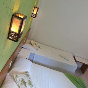 a small room with two beds and two lights at Pousada Dom Capudi in Bombinhas