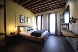 1 dormitorio con 1 cama y TV en Antigua Trece Hotel Fusión en Guanajuato