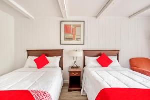a bedroom with two beds with red pillows and a chair at OYO Inn Kernersville in Kernersville