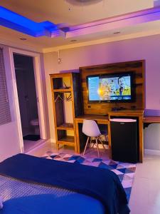 a bedroom with a bed and a tv on a desk at MarBella alugueis de quartos in Penha