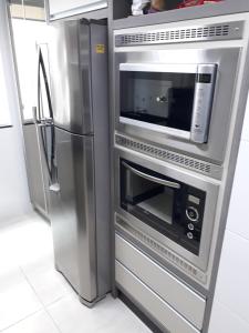 a kitchen with a microwave and a refrigerator at Bombinhas - Residencial Atalanta 101A in Bombinhas