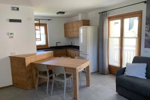 a kitchen with a wooden table and a couch at Mansarda Tresero- Residenza Vallecetta 2 in Piatta
