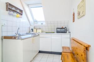 a small white kitchen with a sink and a window at Falkennest 2 in Westerland (Sylt)