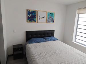 a bedroom with a bed and three pictures on the wall at 4 Apartaestudio Cedritos completo in Bogotá